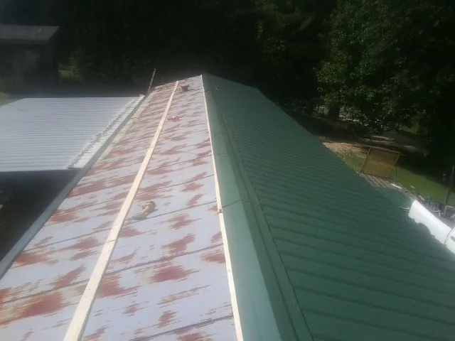 Old rusted panels beside newly installed green metal roofing — Wind Damage Roof Repair by Roofing Brothers in Englishtown