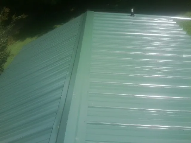 New green metal panels meeting at the ridge of a roof — Flat Roof Repair work by our crew in Englishtown