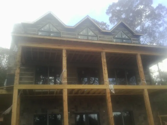 Dormers and porch framing on a large log home under construction — Roof Coating work by our crew in Englishtown