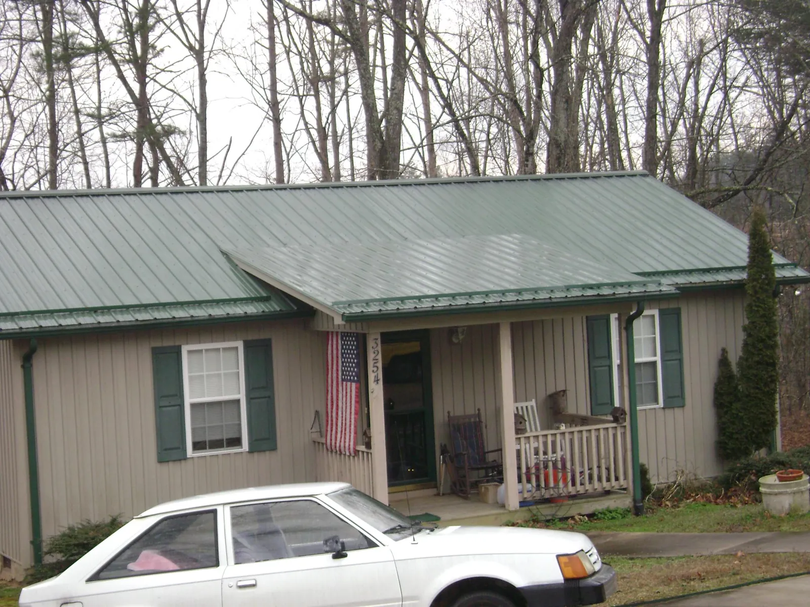 Green metal roof and front porch on a tan sided cottage in Englishtown