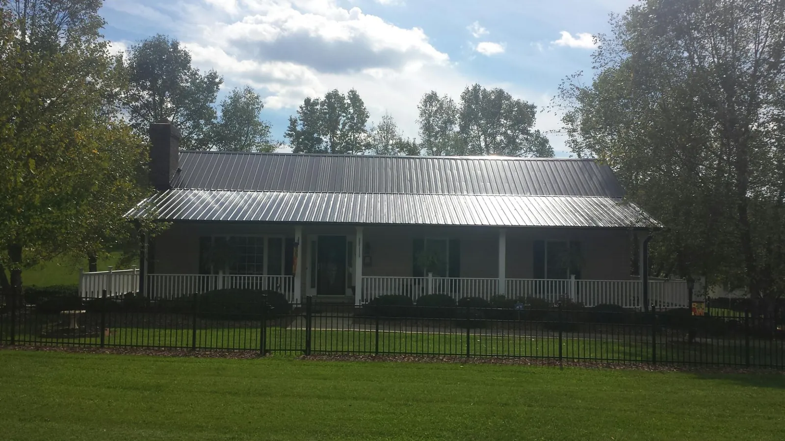 Gray metal roof on a brick ranch with a full width front porch — Gutter Guard Installation work by our crew in Englishtown