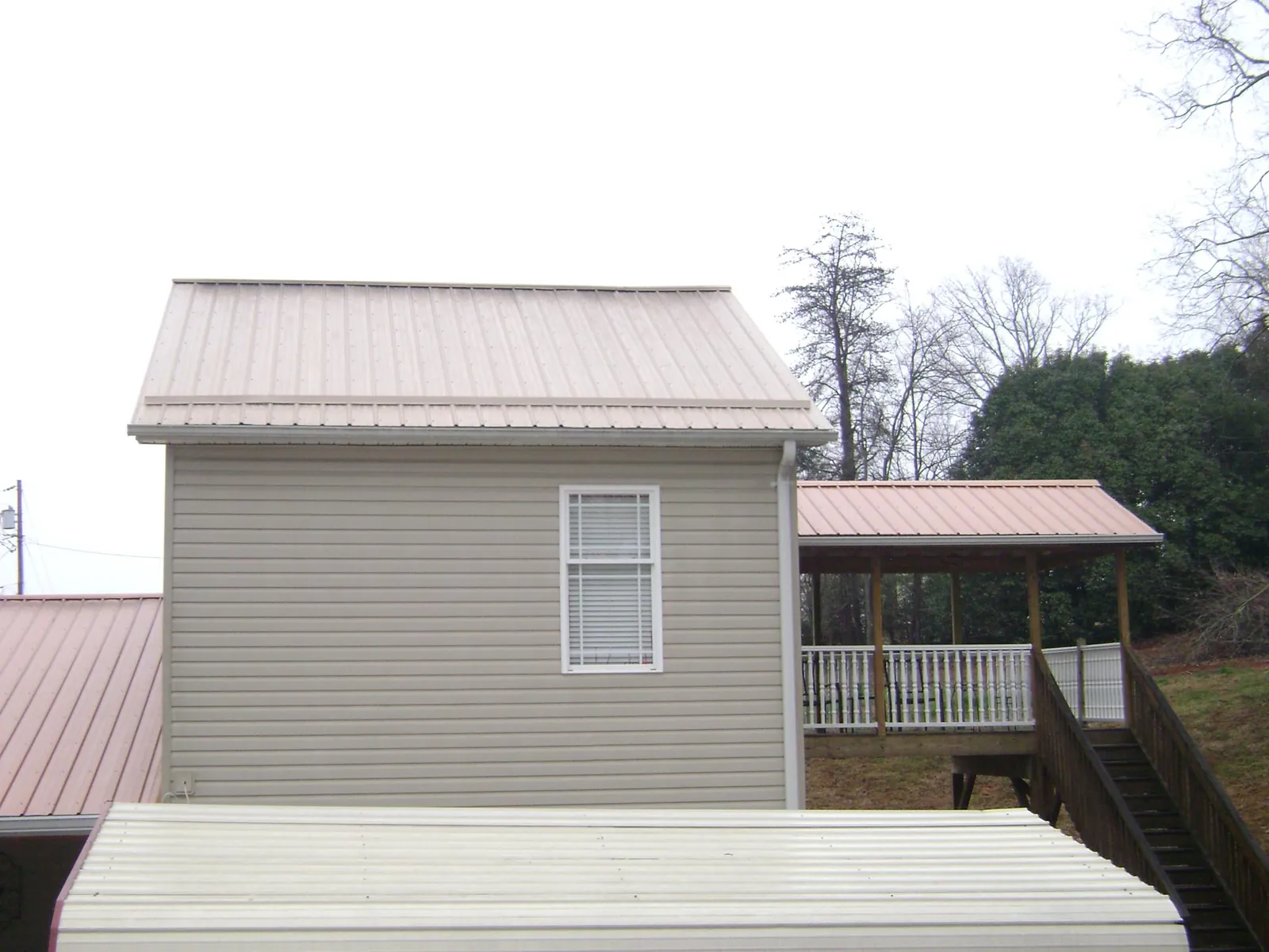 Tan metal roofs on a two story addition and attached porch, from a Roof Replacement job in Englishtown