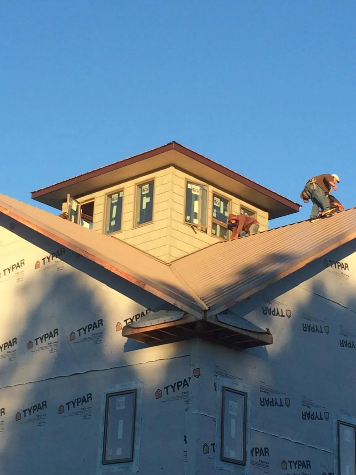 Roofers working around a rooftop cupola on a new metal roof at sunset — Roof Waterproofing in Englishtown by Roofing Brothers